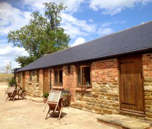 a brick building with two chairs in front of it at Slapton Manor in Towcester