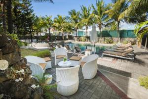 een patio met stoelen en een zwembad met palmbomen bij Talamba Blue in Blue Bay