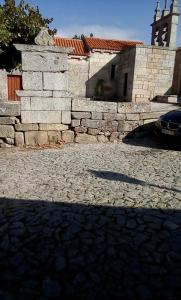 a stone wall and a car parked in front of a building at Casa das Freiras in Marialva