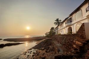 un edificio en la orilla del océano con la puesta de sol en O Pescador an Indy Resort, en Panaji