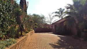 a brick driveway with palm trees and a house at Arek's Place in Krugersdorp