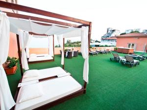 アルムニェーカルにあるバイア トロピカルの緑の芝生の上にベッド2台と椅子が備わる客室です。