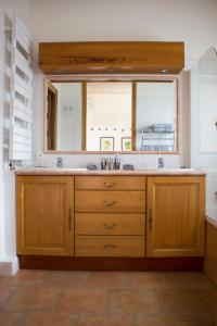 een keuken met een wastafel en een grote spiegel bij Les Clèdes du Mazel in Banne