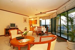 a living room with a table and a dining room at Grand Diamond Suites Hotel in Bangkok