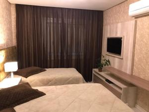 a hotel room with two beds and a television at Altos da Bela Vista Gramado centro locação de temporada in Gramado