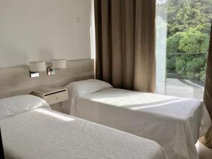 2 camas en una habitación de hotel con ventana en Tila Playa en Las Gaviotas