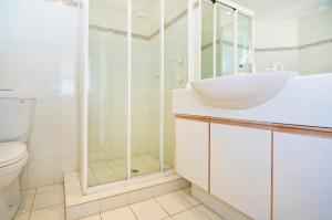 ein weißes Bad mit einem Waschbecken und einer Dusche in der Unterkunft Oceanside Resort - Absolute Beachfront Apartments in Gold Coast