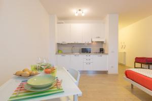 トスコラーノ・マデルノにあるPiantù Homeの白いキャビネットとテーブル(食べ物付)が備わるキッチン