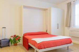 トスコラーノ・マデルノにあるPiantù Homeのベッドルーム1室(赤いシーツとスーツケース付きのベッド1台付)