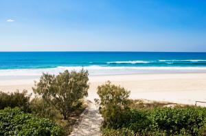 un camino a la playa con el océano en el fondo en Oceanside Resort - Absolute Beachfront Apartments, en Gold Coast
