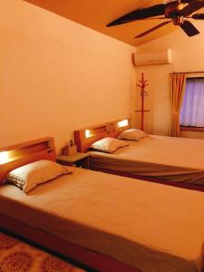 1 dormitorio con 2 camas y ventilador de techo en HimawariRyokanひまわり旅館 en Okayama