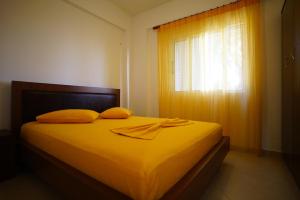 a bedroom with a bed with yellow sheets and a window at Apartments Vila Emiliano in Borsh