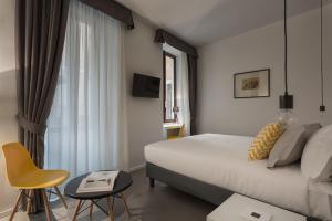 a bedroom with a bed, chair, desk and a lamp at Navona Theatre Hotel in Rome