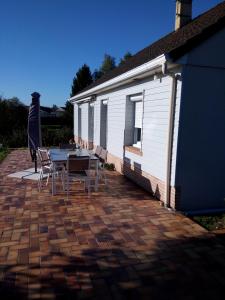 een patio met een tafel en stoelen naast een gebouw bij La Risloise in Corneville-sur-Risle