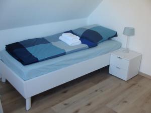 a bed with a blue comforter and a night stand at Ferienhaus Landblick in Geldern