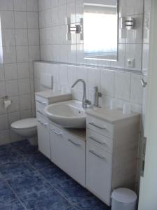 a white bathroom with a sink and a toilet at Ferienhaus Landblick in Geldern