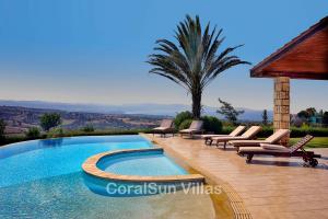 a swimming pool with lounge chairs and a palm tree at ELITE Amazing Villa, by Coral Sun Villas in Polis Chrysochous
