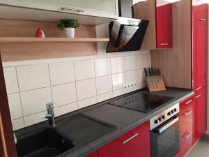 una cocina con fregadero negro y armarios rojos en LANE City Laatzen en Hannover