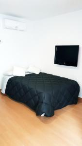 een zwart bed in een kamer met een flatscreen-tv bij Alda Benalmadena in Benalmádena