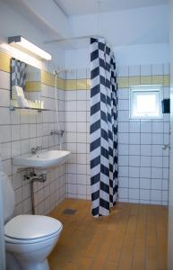 a bathroom with a black and white shower curtain and a toilet at Hotel Hvideklit in Ålbæk