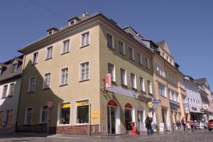 a building on a street with people walking in front of it at Pension & Ferienwohnungen Töpferstüb'l in Saalfeld