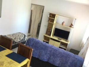 a living room with a blue couch and a tv at Casa na Vila do Chicão in Aracaju