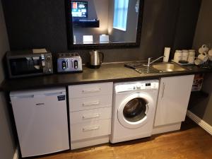 a kitchen with a washing machine and a sink at Chatterley House in Nottingham