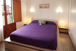 Cama morada en habitación con 2 mesitas de noche en La Casita Delfin Azul, en Sa Ràpita