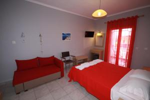 a bedroom with a red bed and a red couch at ZEPHYROS ROOMS in Ormos Panagias