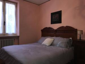 a bedroom with a bed with a wooden headboard and a window at Bed & Roses “Gege” in La Morra