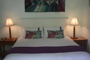 a bedroom with a white bed with two lamps at Meander In in Howick
