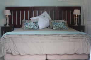 a large bed with pillows on it with two lamps at Meander In in Howick