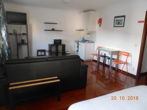 a living room with a black couch and a kitchen at Sinos Rio Tinto in Campainha
