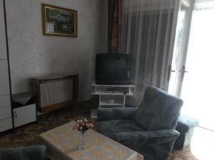 ein Wohnzimmer mit einem TV, 2 Stühlen und einem Tisch in der Unterkunft Livia Apartman in Balatonföldvár