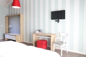 a bedroom with a bed and a desk and a tv at Namib Guesthouse in Swakopmund