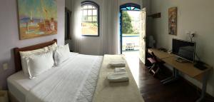 um quarto com uma cama, uma secretária e uma televisão em Abigail Condé em Ouro Preto