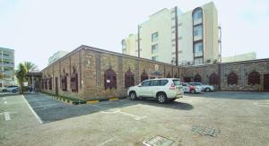 uma carrinha branca estacionada num parque de estacionamento ao lado de um edifício de tijolos em Mutrah Hotel em Mascate