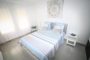 Castillo del RomeralにあるApartment am Meer 2/ At the Seaのベッドルーム1室(青と白のストライプの毛布付きのベッド1台付)