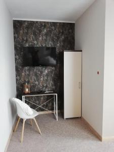 a room with a white chair and a television on a wall at Pokoje gościnne 30stka in Łęczna