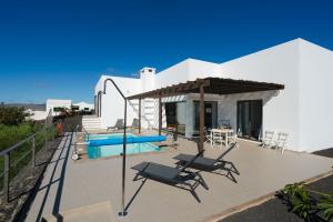 a villa with a swimming pool and chairs on a deck at El Tucan, excelentes vistas y privacidad in Nazaret
