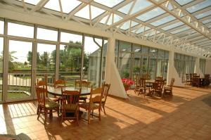 einen Wintergarten mit einem Tisch, Stühlen und Fenstern in der Unterkunft Ąžuolynas in Juodkrantė