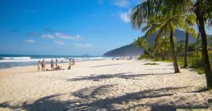 a group of people on a beach with palm trees at Estúdio em maresias com ar condicionado e piscina in Maresias