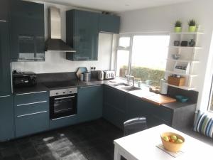 una cucina con armadi blu, lavandino e finestra di Dalriada Crescent a Cushendall