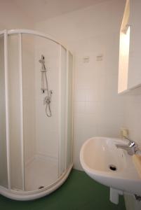 baño blanco con ducha y lavamanos en Elena, en Lignano Sabbiadoro