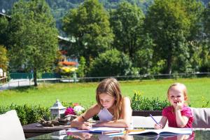deux petites filles assises à une table en lisant des livres dans l'établissement KENDLGUT Appartements am BioBauernhof inklusive unbegrenztem Eintritt in die Alpentherme, à Bad Hofgastein
