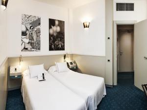 two beds in a hotel room with white sheets at Hotel Milano in Padova