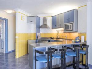 a kitchen with a counter and some blue stools at Apartamento Mar y Sol in Puerto de la Madera