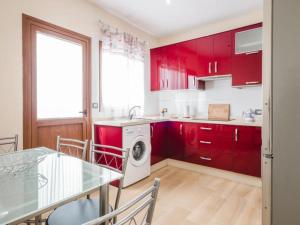 a kitchen with red cabinets and a table and a washing machine at apartamento tenerife in Icod de los Vinos