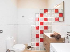 a bathroom with a white toilet and a red and white tile wall at apartamento tenerife in Icod de los Vinos