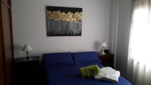 Un dormitorio con una cama azul y una pintura en la pared en Dpto San Martin en Salta